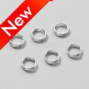 May include: Silver jump rings, a type of jewelry finding, are arranged in a circle on a white surface. The jump rings are double-looped and are approximately 10mm in diameter.