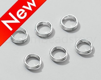 May include: Silver jump rings, a type of jewellery finding, are arranged in a circle on a white surface. The jump rings are double-looped and are approximately 10mm in diameter.