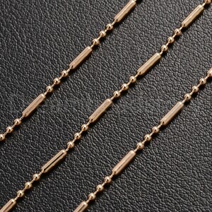 May include: A gold chain necklace with a repeating pattern of small round beads and longer, rectangular beads.