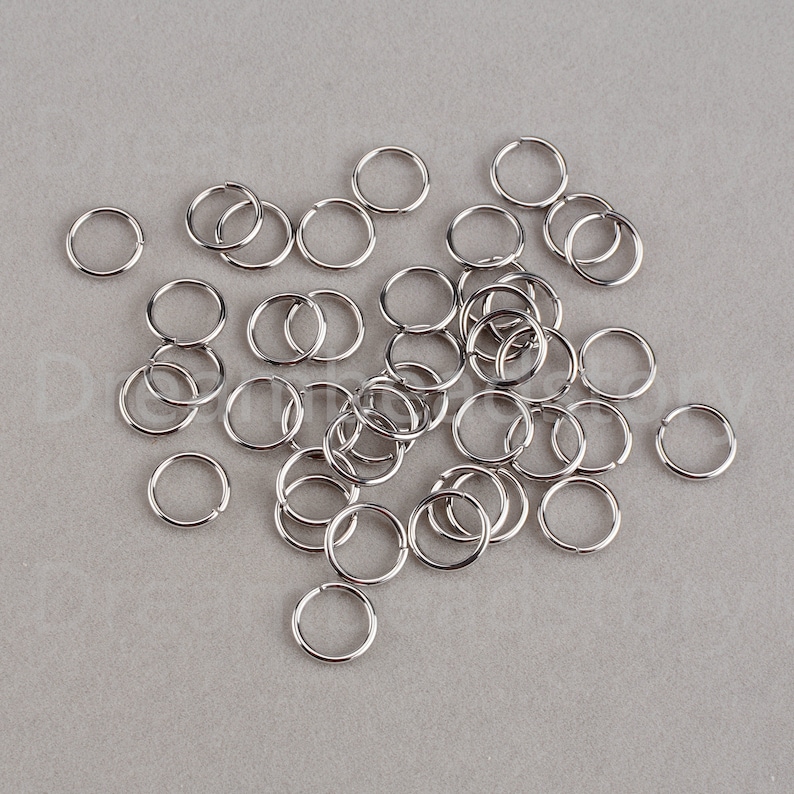 May include: A pile of silver jump rings, a type of metal ring used in jewelry making.