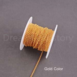 Peut inclure: Une bobine de cha&icirc;ne de couleur or, enroul&eacute;e autour d'une bobine en plastique blanc. La cha&icirc;ne est de style d&eacute;licat &agrave; maillons fins.