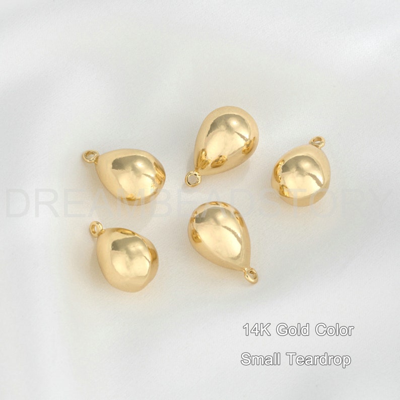 Peut inclure: Cinq breloques en forme de goutte d'eau de couleur or avec une boucle en haut. 14K Gold Color Small Teardrop.