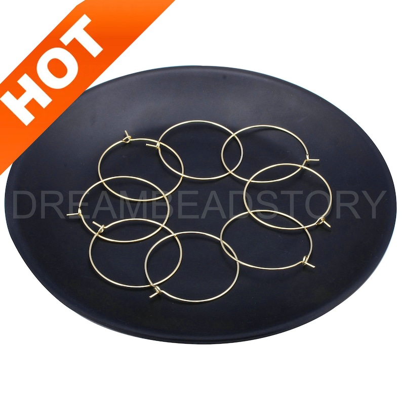 May include: Six gold hoop earrings on a black plate. The earrings are simple and elegant.