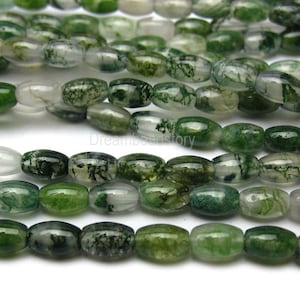 Può includere: Una collana di perline di agata muschio verde. Le perline sono di forma ovale e hanno un colore verde traslucido con inclusiones verde scuro che assomigliano a muschio.