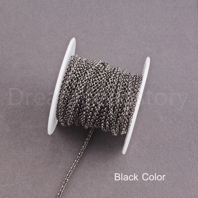 Peut inclure: Une bobine de cha&icirc;ne noire, enroul&eacute;e autour d'une bobine en plastique blanche. La cha&icirc;ne est fine et d&eacute;licate.