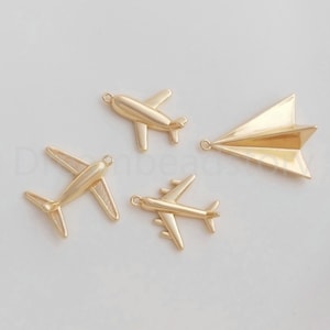 以下が含まれることがあります： 飛行機と紙飛行機の形をした金色の金属製のチャームが4つ。ジュエリーやクラフトに旅行のテーマを追加するのに最適です。