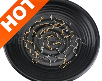May include: A collection of gold and silver earring hooks on a black plate. The hooks are made of metal and have a small loop at the top. They are perfect for making earrings.