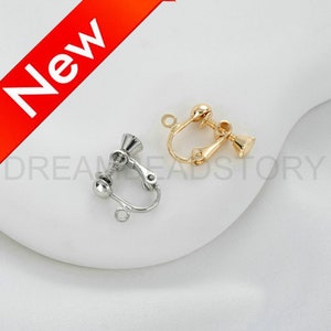 May include: Two earring clips, one silver and one gold, with a screw-on design. The clips are designed to hold earrings in place.