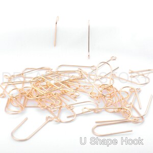 May include: A pile of gold-colored U-shaped hooks. The hooks are made of metal and are about 1 inch long.  U Shape Hook