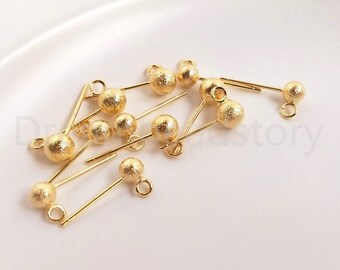 May include: A group of gold-toned earring findings with a textured ball at the end of each finding. The findings have a loop at the top for attaching to jewellery.