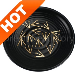 Puede incluir: Hallazgos de joyería dorados en forma de V con tres agujeros en los extremos, esparcidos sobre un plato negro. La palabra "HOT" se muestra en letras blancas sobre una pancarta naranja en la esquina superior izquierda. La imagen está bien iluminada.