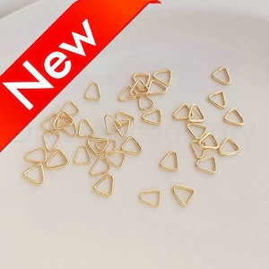 Könnte beinhalten: Eine große Menge goldfarbener, dreieckiger Metall-Sprünge. Die Sprünge sind klein und filigran.