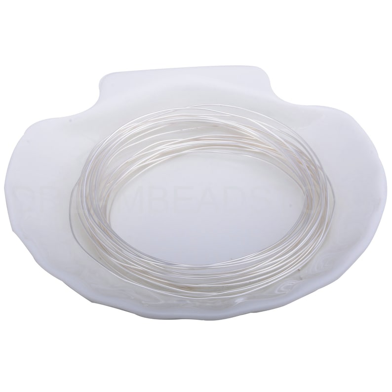 Pode incluir: Um rolo de fio de prata em um prato branco em forma de concha.