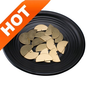 May include: A collection of gold-colored metal half-circle shapes with holes in the center, displayed on a black plate.