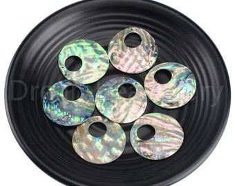 May include: Seven iridescent abalone shell pendants with a circular design and a hole in the center, displayed on a black plate. The shells have a mix of green, blue, and purple hues.