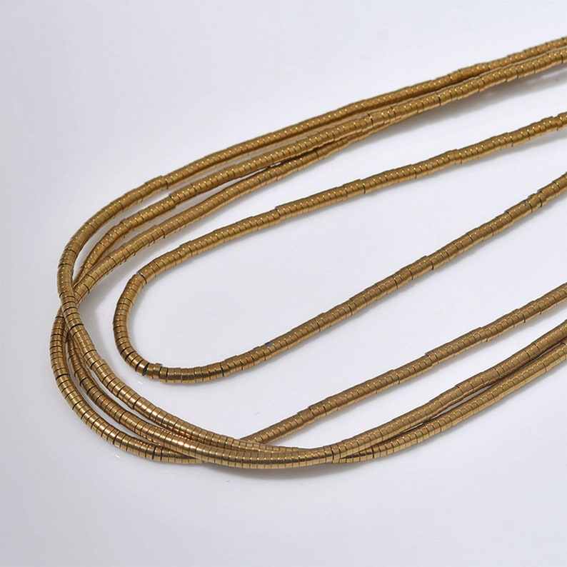 Pu&ograve; includere: Una collana d'oro realizzata con piccole perle rotonde. La collana &egrave; a strati, creando un aspetto multifilo.