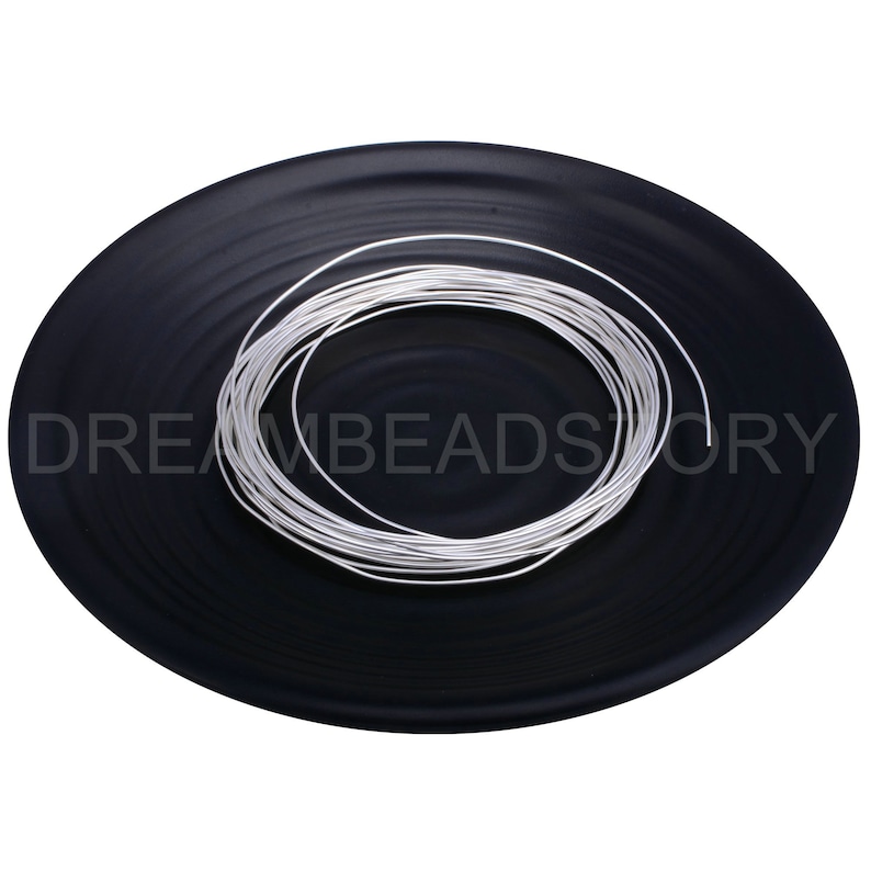 Pode incluir: Uma bobina de fio prateado em um prato preto. O fio tem aproximadamente 1 mm de espessura.