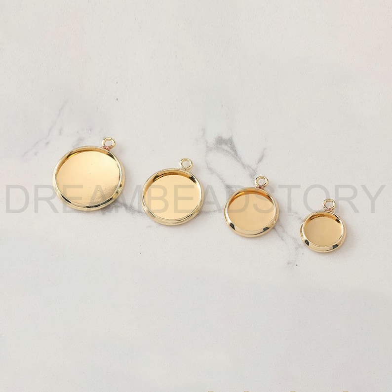 Puede incluir: Cuatro bandejas de colgantes de metal dorado de diferentes tama&ntilde;os. Las bandejas son redondas y tienen un acabado liso y brillante. Son perfectas para crear joyas personalizadas.