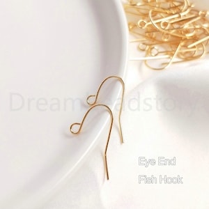 May include: Two gold-toned eye end fish hook earring findings.