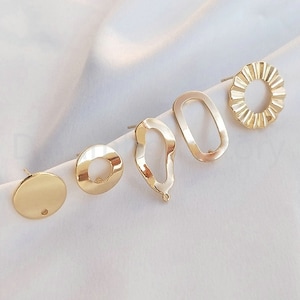 Puede incluir: Conjunto de cinco pendientes de color dorado con diferentes formas geométricas, incluyendo un círculo, un óvalo y una forma libre. Los pendientes son todos pequeños y delicados.