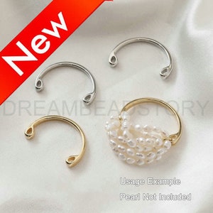 Puede incluir: Tres anillos de plata y oro con una abertura en forma de lágrima en cada extremo. Los anillos se muestran sobre una superficie blanca. El anillo de oro se muestra con una hebra de perlas blancas envuelta alrededor. El texto "Ejemplo de uso" y "Perla no incluida" se muestra debajo de los anillos.