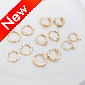 May include: A set of ten gold-toned hoop earring findings with jump rings. The findings are arranged in two rows on a white surface.
