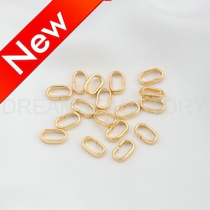 May include: A group of 18 gold-toned oval jump rings. The rings are approximately 1 cm in diameter and are scattered on a white surface.