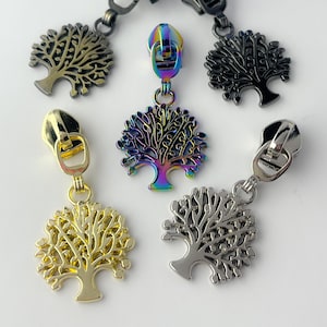 May include: Five zipper pulls with tree-shaped charms. The charms are in different colors, including gold, silver, black, and iridescent.
