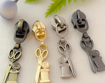 May include: Four zipper pulls with a sewing theme. Each pull features a pair of scissors and a spool of thread. The pulls are available in gold, silver, antique brass, and black.
