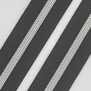 May include: Two black zipper tapes with silver metal teeth. The zipper tapes are laid out side by side.
