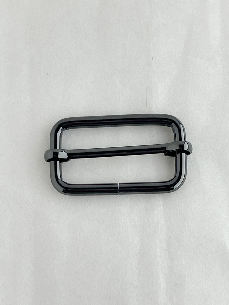May include: A black metal buckle with a rectangular shape and a smooth finish.
