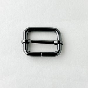 May include: A black metal slider buckle for a strap or belt.