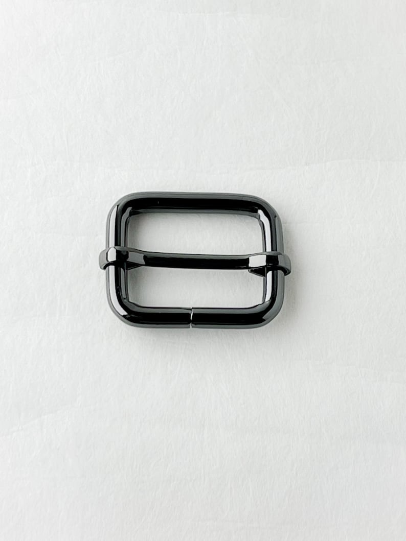 May include: A black metal slider buckle for a strap or belt.