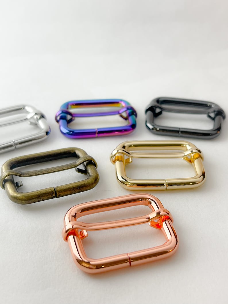 May include: Assortment of metal slider buckles in various finishes, including silver, rainbow, black, gold, and rose gold. These buckles are ideal for crafting and DIY projects.