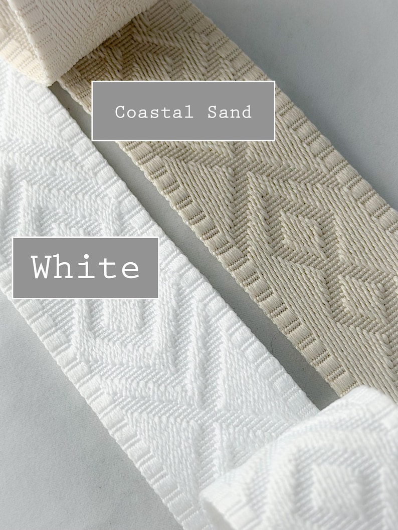 K&ouml;nnte beinhalten: Zwei Rollen gewebtes Stoffband mit einem geometrischen Rautenmuster. Eine Rolle ist mit White beschriftet und ist strahlend wei&szlig;, w&auml;hrend die andere mit Coastal Sand beschriftet ist und eine hellbeige Farbe hat. Beide B&auml;nder haben ein strukturiertes Gewebe.