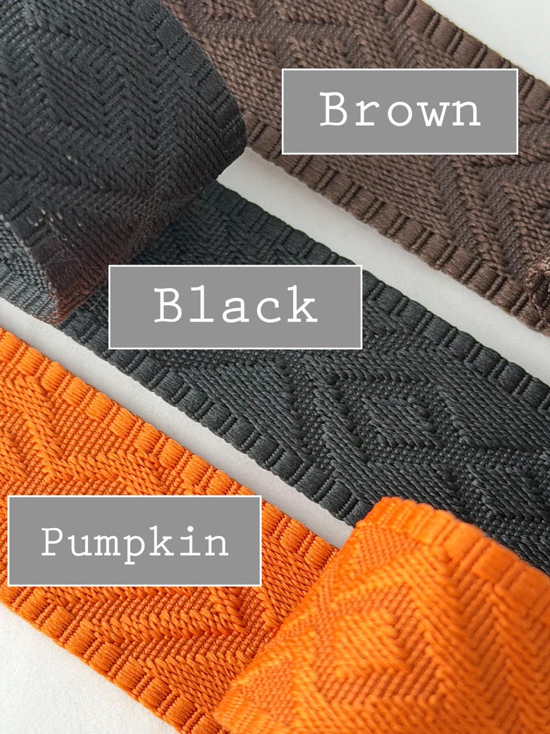K&ouml;nnte beinhalten: Drei Streifen aus gewebtem Stoffbesatz mit einem geometrischen Rautenmuster. Die Farben sind als Brown, Black und Pumpkin beschriftet. Jeder Streifen weist ein strukturiertes, erhabenes Gewebe mit einem durchgehenden Muster auf.