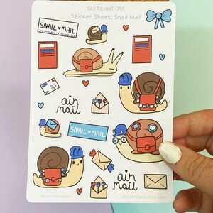 May include: A sticker sheet with a snail mail theme. The sheet features illustrations of snails carrying mail, mailboxes, envelopes, and the text "snail mail" and "air mail".