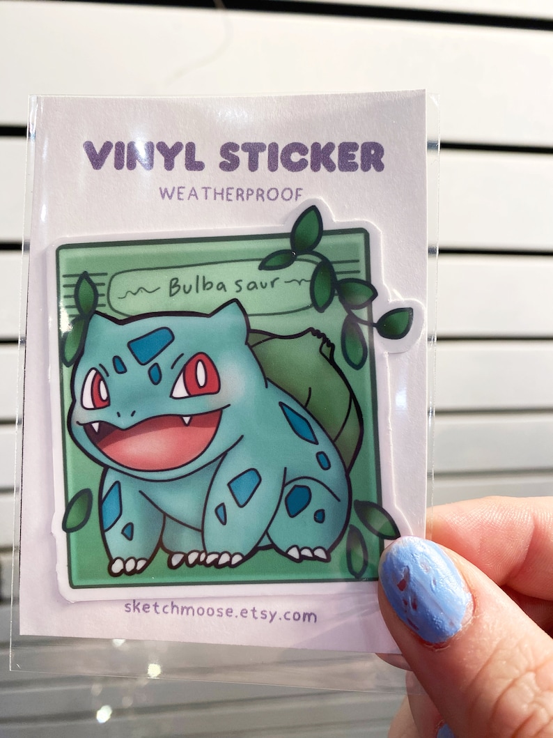 May include: A vinyl sticker featuring a cartoon Bulbasaur, a green and blue Pokemon, with a green background and vines. The sticker is weatherproof and says "~Bulbasaur~" and "sketchmoose.etsy.com".