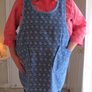 May include: A blue and white floral print apron with two pockets. The apron has a scoop neck and adjustable straps.
