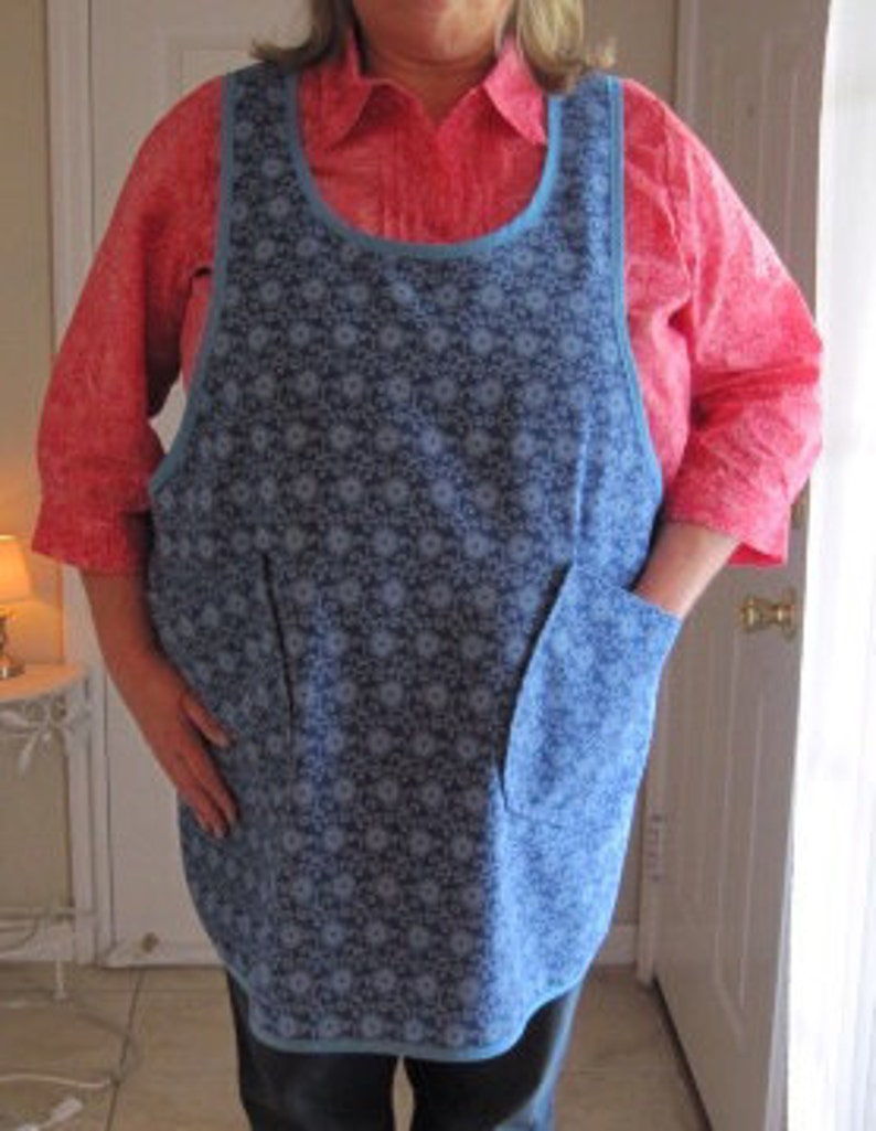 May include: A blue and white floral print apron with two pockets. The apron has a scoop neck and adjustable straps.