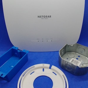 May include: A white NETGEAR INSIGHT device with a rounded square shape, accompanied by a blue electrical box, a white mounting plate, and a metal electrical box. The words "Parts & Technology" are at the bottom.