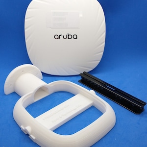 May include: White ceiling-mounted wireless access point with the word "aruba" printed on it. The access point is shown with its mounting bracket and a black metal mounting rail.