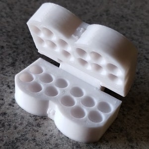 May include: White plastic pill organizer with two hinged sections. Each section has multiple round compartments for storing pills.