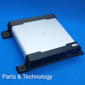 May include: A black plastic case with a silver device inside. The device has a U logo on the top. The case has a small hole on the side.