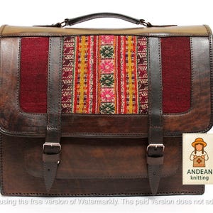May include: A brown leather satchel with a colorful woven textile panel. The bag features a top handle, two buckle closures, and a rectangular shape. The textile panel has red, yellow, and pink patterns. The bag has a tag that says "ANDEAN knitting".