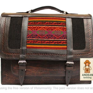 May include: A brown leather satchel with a colorful woven panel. The bag features a top handle, two front straps with buckles, and a rectangular shape. The woven panel has red, orange, green, and purple geometric designs. The bag has the text "ANDEAN knitting".