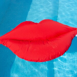 May include: A bright red inflatable pool float shaped like a pair of lips.