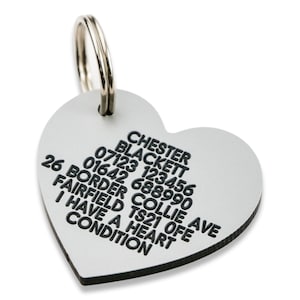 May include: Silver heart-shaped dog tag with black text. The text reads: "CHESTER BLACKETT 07123 123456 26 BORDER COLLIE AVE 01642 688990 FAIRFIELD TS21 OFE I HAVE A HEART CONDITION"