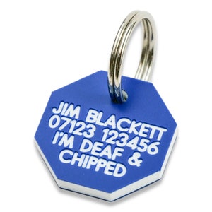 May include: Blue octagon-shaped dog tag with white text that reads "JIM BLACKETT 07123 123456 I'M DEAF & CHIPPED". The tag has a silver metal ring.