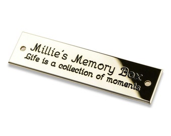 May include: A gold-colored metal plaque with the text "Millie's Memory Box Life is a collection of moments".